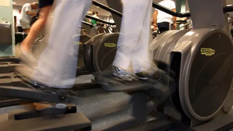 A close-up of a blurred pair of legs on an exercise machine. 