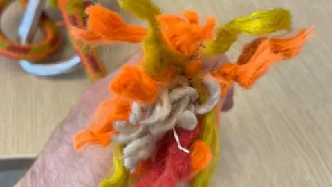 HSE Orange rope fibres which have snapped. A man is holding up the rope.