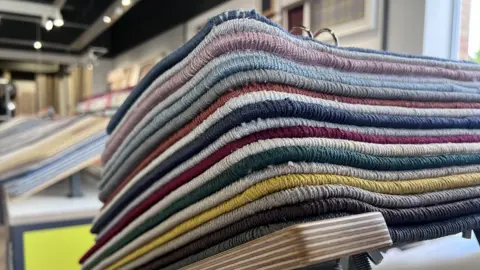 Kris Holland/BBC A stack of carpets in different colours