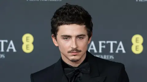 Future Publishing via Getty Images Headshot of Chalamet who wears a black suit and bowtie in front of a black background which says Bafta awards on it 