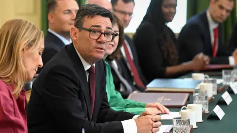 Burham looks up and towards the camera while sitting at a desk surrounded by cabinet members during a cabinet meeting in Downing Street on 21 July.