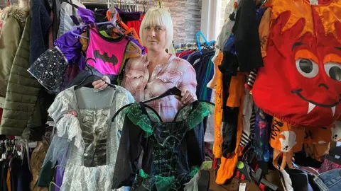 BBC Jen Wake at Uniform for all Northumberland, holding two girls' Halloween costumes