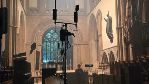 Llandaff Cathedral An interior image of Llandaff Cathedral, with a camera boom and sound equipment next to pews.