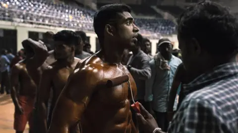 Tight: The World of Indian Bodybuilding A bodybuilder waits in line