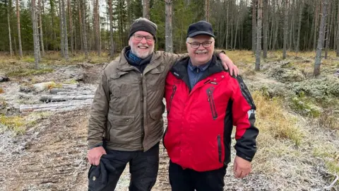 Two men with their arms round each other in an outside space