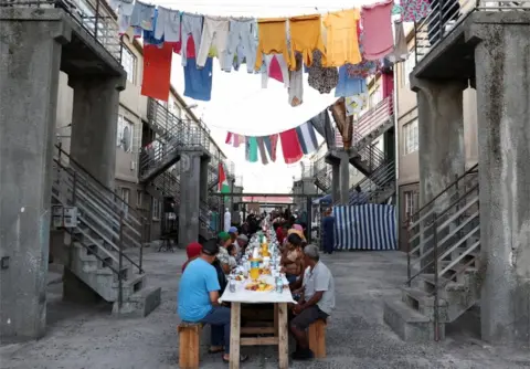 ESA ALEXANDER/REUTERS People sit at a long makeshift table in Heideveld on 30 March.