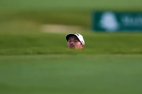 ANGEL MARTINEZ/GETTY IMAGES A man peers above the ground in front of him. Only his head is visible.