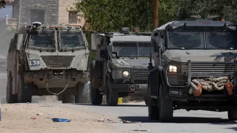sraeli troops deployed during a military operation in the eastern neighbourhood of the West Bank city of Jenin, 21 May 2025 - three green army vehicles 