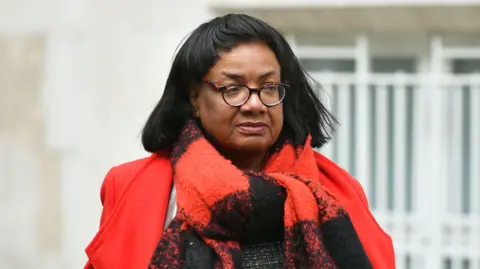 PA Media Diane Abbott wearing a red coat