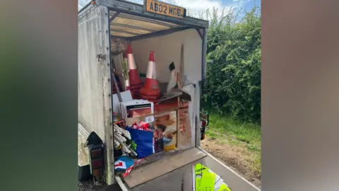 A view of a trailer packed with high vis jackets, cones and other kit used to stage a road race