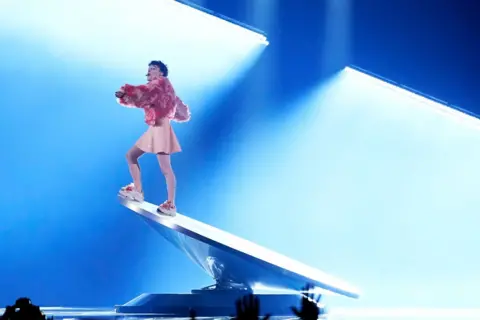 Getty Images Nemo stands on a tilted rotating platform at the 2024 Eurovision Song Contest