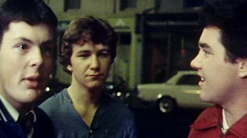 Three young men speaking into the camera, on the street.