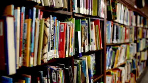 Books are crowded on a shelf. 