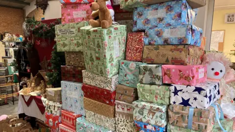 A large pile of shoeboxes wrapped in festive wrapping. 