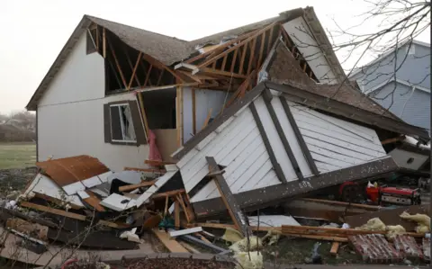 Debris piled around a downed home in Florissant, Missouri on 15 March