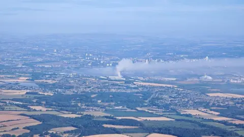 An aerial picture of Leeds and the surrounding countryside with a large plume of smoke rising and blowing east across the city