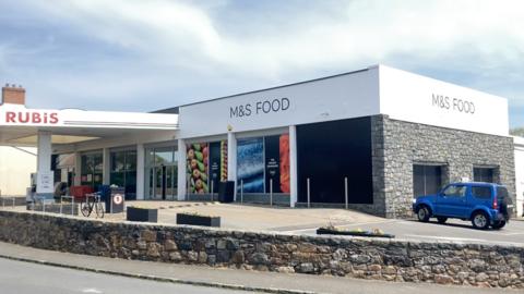 Marks and Spencer foot in St Martin's. A grey, square building with a small petrol station attached.