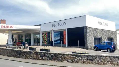 BBC Marks and Spencer foot in St Martin's. A grey, square building with a small petrol station attached.