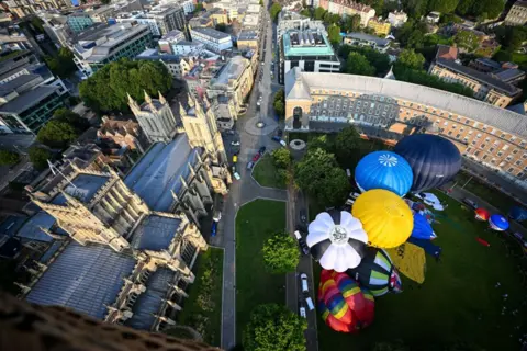 Finnbarr Webster/Getty Images A fleet of hot air balloons take off from College Green and Queen Square to mark the countdown to the 46th Bristol International Balloon Fiesta on July 24, 2024 in Bristol, England