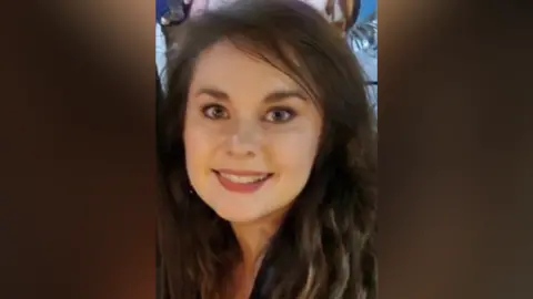 A close up of a woman with black hair smiling.