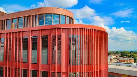 Gloucester City Council The top two stories of the development, showcasing the red panelling and curved frontage. 