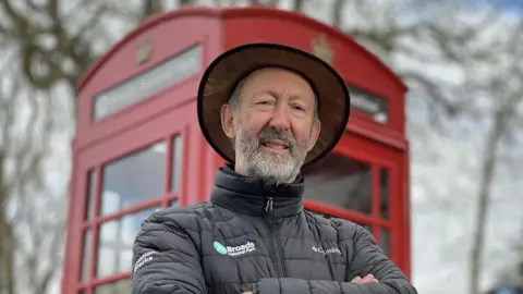 John Packman outside a red phonebox in Thurne