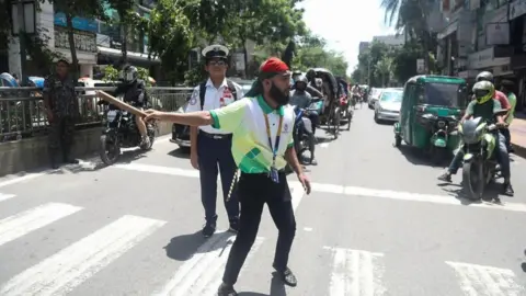 EPA A Bangladeshi student tries to control traffic as traffic police fail to show up for duty, in Dhaka, Bangladesh, August 7, 2024. In an address to the nation, Chief of Army Staff General Waker-Uz-Zaman announced on August 5 that Prime Minister Sheikh Hasina had resigned after weeks of unrest and that an interim government would be formed to run the country. The press secretary of the President of Bangladesh announced on August 7 that Muhammad Yunus had been chosen as the interim leader of Bangladesh following the resignation of former Prime Minister Sheikh Hasina. Dhaka after Bangladeshi prime minister's resignation, Bangladesh - August 7, 2024