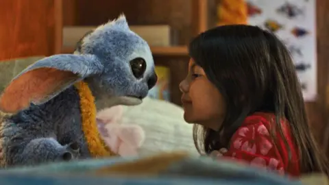 Furry alien Stictch nose-to-nose with young girl Lilo in a still from the Lilo and Stitch remake