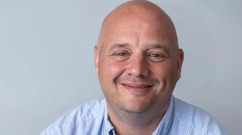 Telford & Wrekin Council Publicity shot of Lee Carter, smiling and wearing a blue checked shirt.