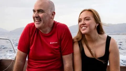 BBC/Studio Lambert a man and woman on a boat, with mountains in the background