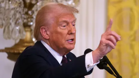 EPA Donald Trump extending his hand at a lectern at the White House 