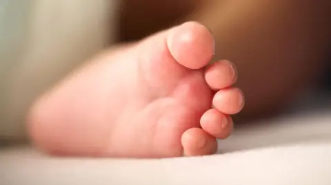 Stock image of a baby's foot on a white cloth