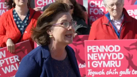Eluned Morgan Labour supporters with placards in the background