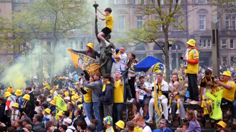 Reuters / Ed Sykes Fans gather and hold flags, with a young boy sitting atop a statue
