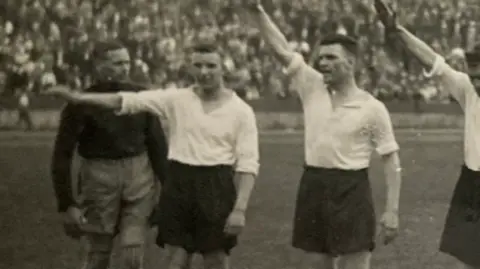 A group of Derby County players performing a Nazi salute on a football pitch in Germany in 1934