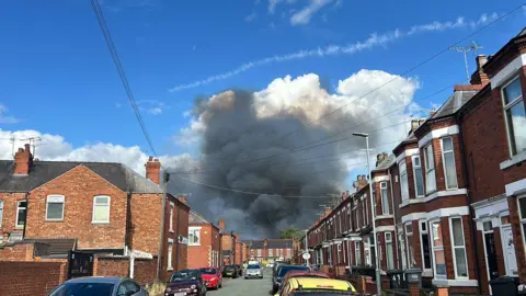 A large plume of smoke can be seen above a row of terraced houses