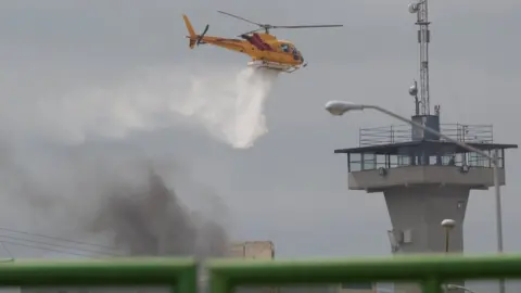Reuters A helicopter drops water to extinguish a fire after a riot broke out at the Cadereyta state prison, in Cadereyta Jimenez
