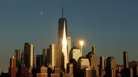 O Getty Imagine é uma lua crescente que se levanta atrás do horizonte da Baixa Manhattan e de Nova Jersey City, Nova Jersey Jersey City, refletindo um World Trade Center enquanto o sol afundava na cidade de Nova York.