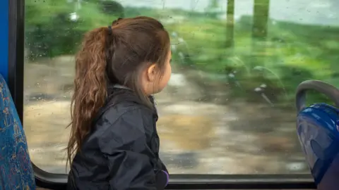 Girl looks out a window on a bus