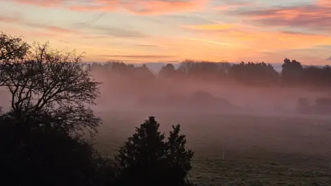 Weather Watchers/Suzukibandit Beautiful winter sunrise over fields with a low mist and trees in the fore and background.