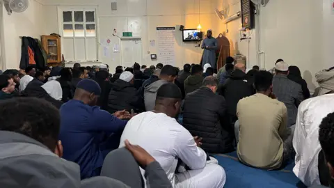 Worshippers sit on the floor of the mosque to listen to the Imam during prayers