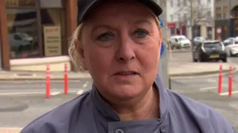 Maria Gough in a purple uniform and hat. Her hair is tied back. 