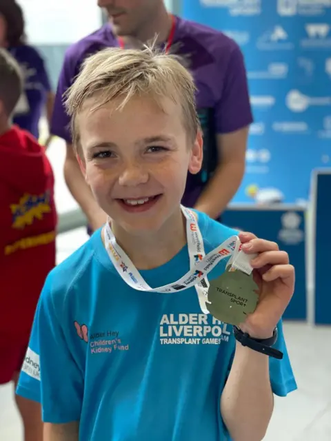 Julie Baddock Alex holding a medal that he won at the summer transplant games 2023