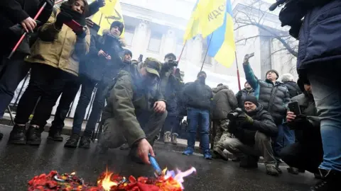 Getty Images Activists burn the Russian flag and St George ribbons - symbols of the so called 'Russian world' - as they call for the deputies to recognise Russia as an aggressor state during a rally in front of the Ukrainian parliament in Kiev, on January 16, 2018