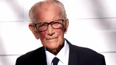 Handout A family photograph showing Len Gibson looking at the camera. He is wearing a white shirt, with a black blazer.