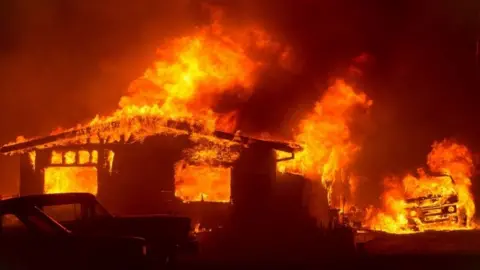 AFP A car and house are engulfed in flames as the "Wall Fire" burns through a residential area in Oroville (09 July 2017)