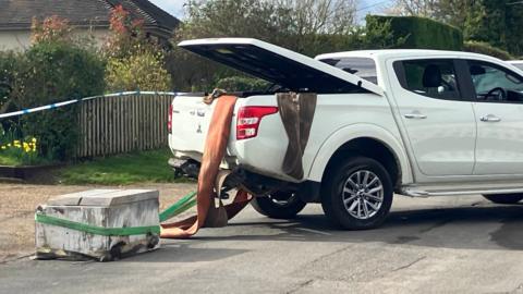 White Mitsubishi L200 with boot open and cash machine attached to the tow bar 