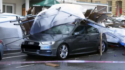 Eddie Mitchell A car is crushed by scaffolding. 