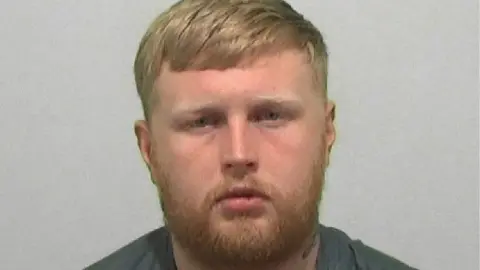 Northumbria Police Mugshot of Jack Fowler. He has short ginger hair and a beard. Fowler also has a neck tattoo.