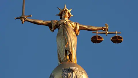 BBC Gold Lady Justice statue holding scales of justice. 